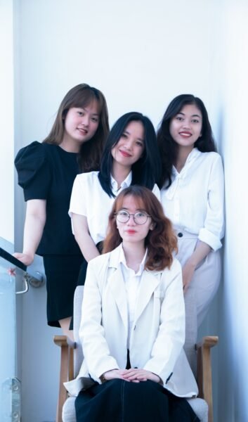 Portrait of four young women smiling and posing together in a bright indoor setting.