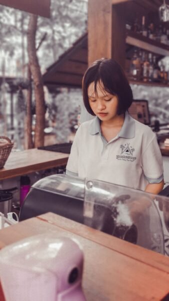Asian woman working at a cafe counter in Kampot Province, Cambodia.