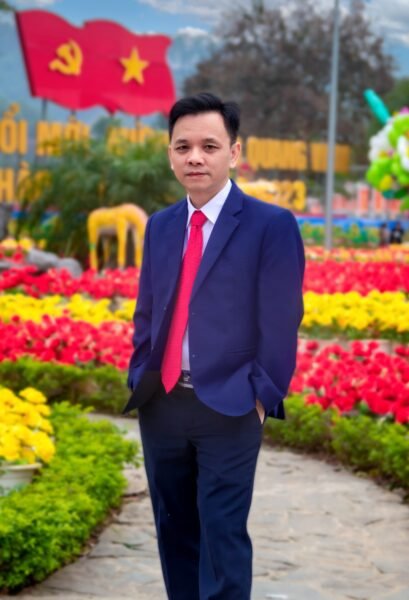 Asian businessman in a blue suit and red tie posing in a colorful flower garden outdoors.