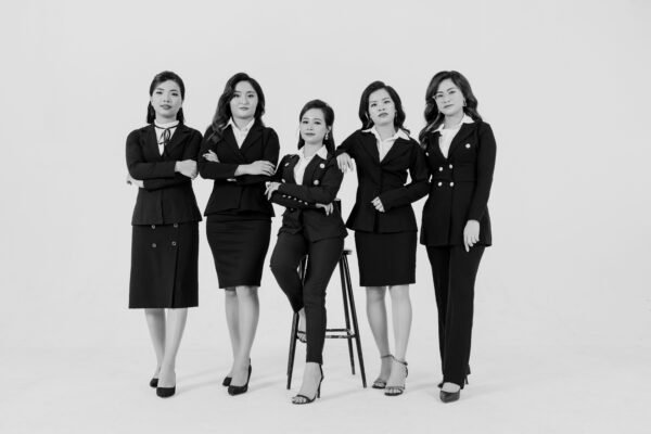 Five confident businesswomen in formal attire, exuding professionalism in a monochrome setting.