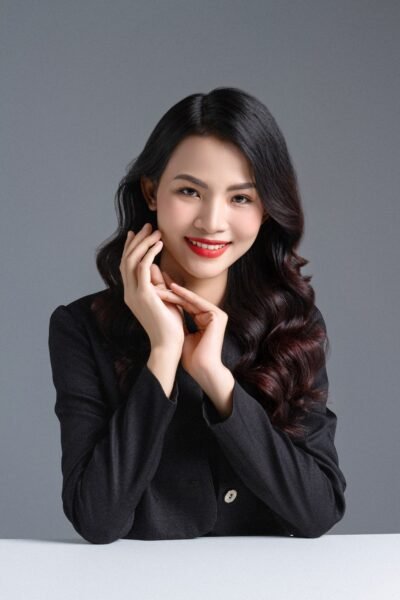 Portrait of a stylish woman in a black shirt posing confidently in a studio setting.