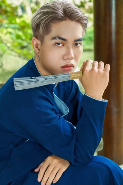 Portrait of a man in traditional Vietnamese attire holding a hand-held fan.
