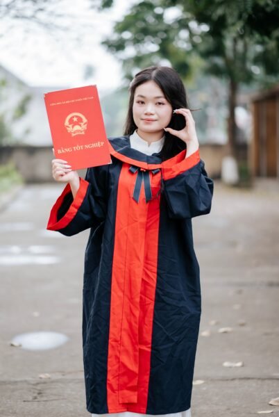 A young graduate proudly holds her diploma certificate outdoors, symbolizing academic achievement.