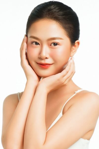 High-key studio portrait of an elegant Asian woman with radiant skin and soft lighting.