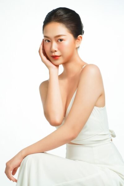 A studio portrait of an elegant Asian woman in white, showcasing beauty and elegance with soft, high-key lighting.