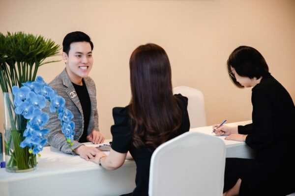 Three professionals engaged in a business meeting at a modern office with vibrant floral decor.