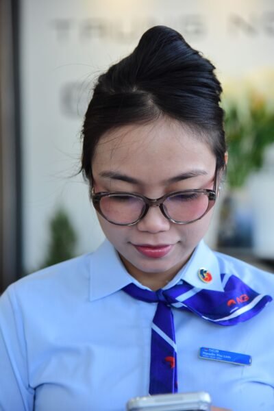 Young businesswoman in uniform reading smartphone indoors.