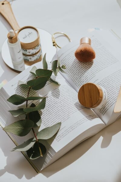 Chic flat lay of skincare products on an open book with green leaves.