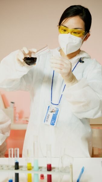 A young scientist in protective gear carefully pouring liquid in a laboratory.